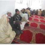 Afghan men sitting in a masjid with red prayer mats