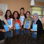 Group of women posing with Daisy Khan and the WISE UP: Knowledge Ends Extremism booklets